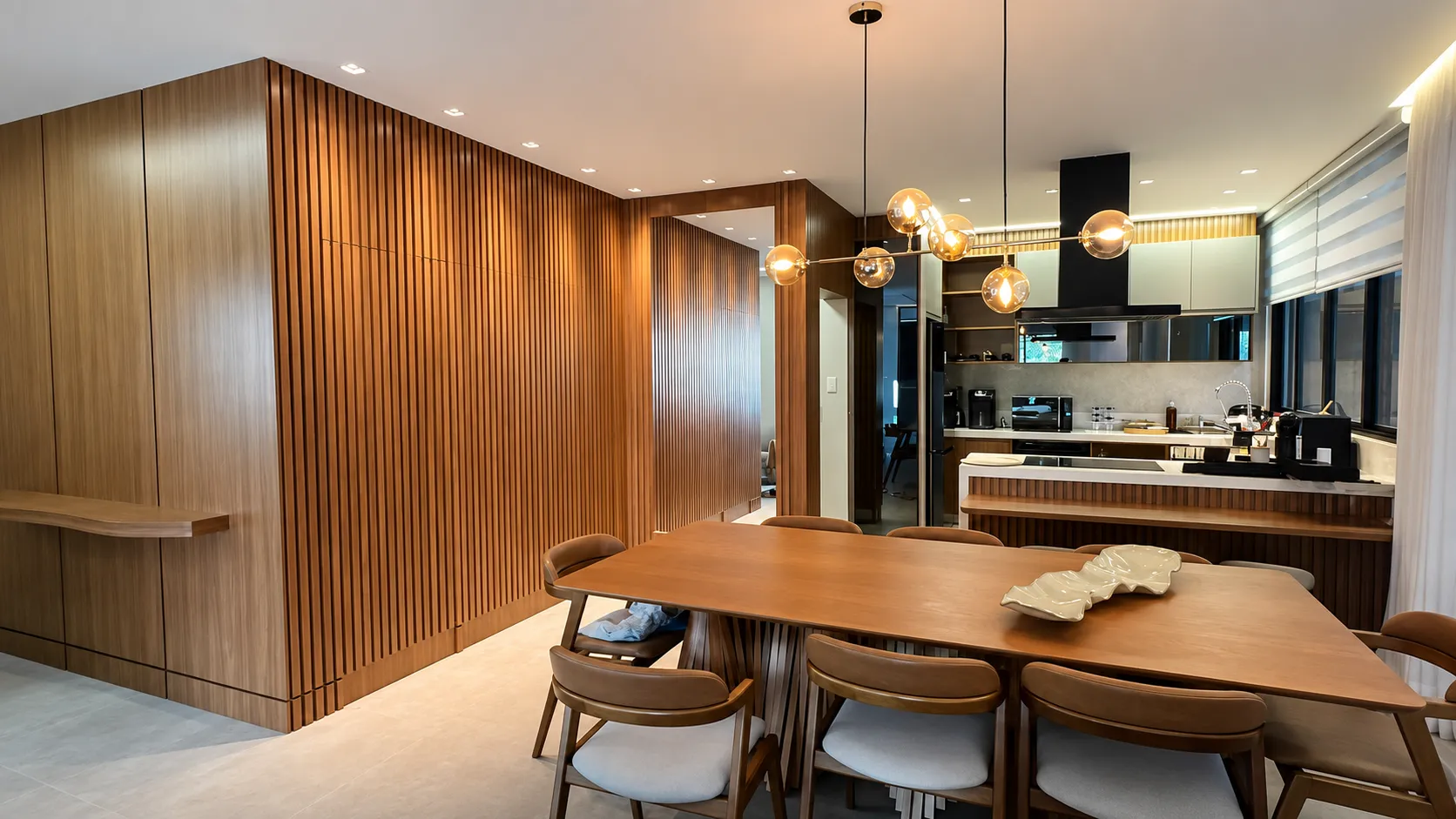 Sala de jantar Onofre com painel ripado de madeira e pendentes decorativos
